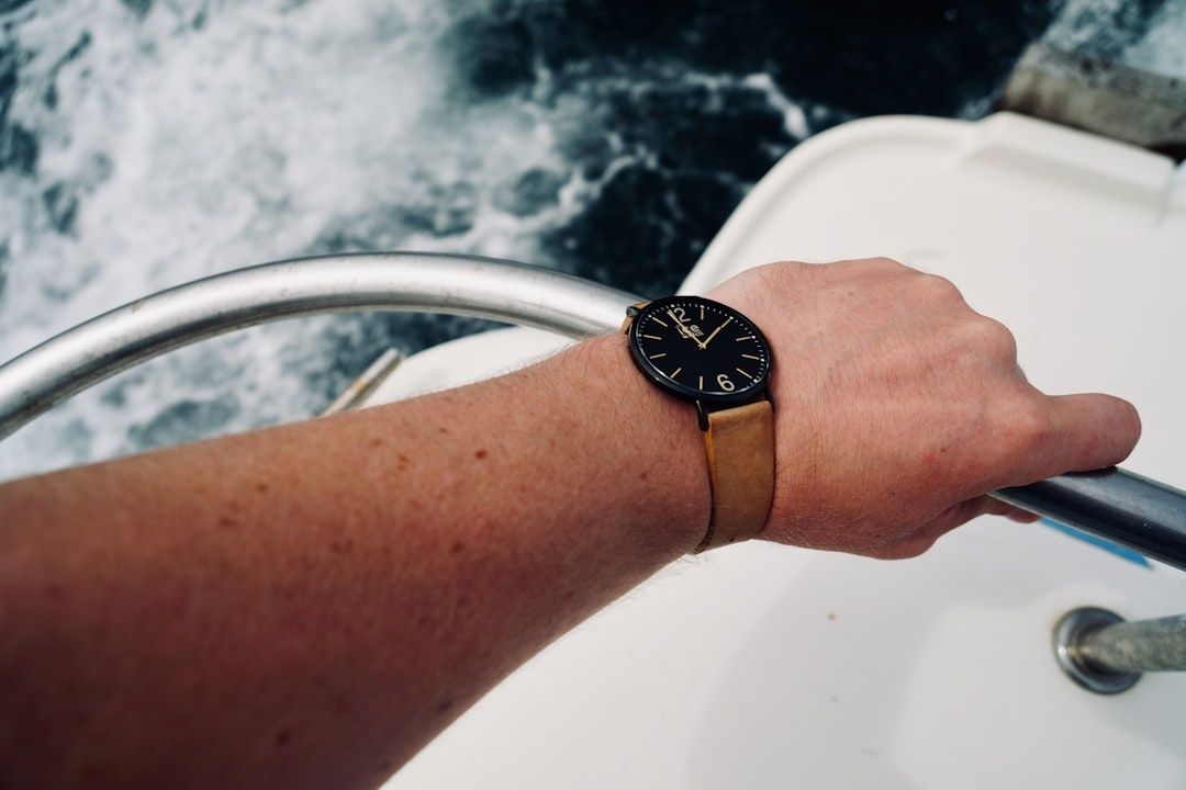 Hand am Steuer eines Boots mit Armbanduhr über bewegtem Wasser